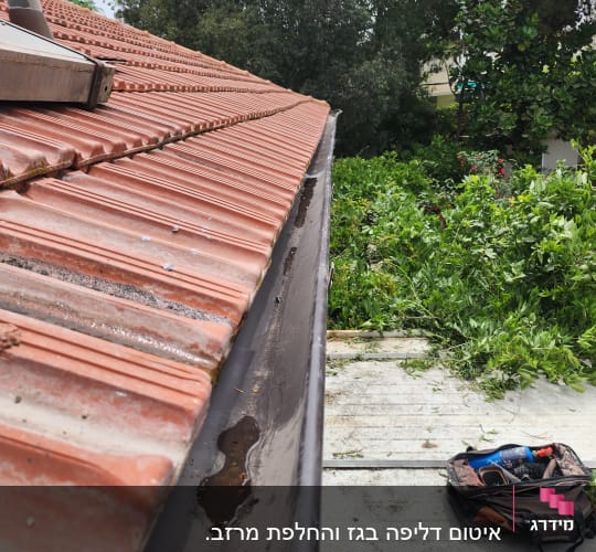 גג רעפים אדום עם מרזב מתכת ומים עומדים